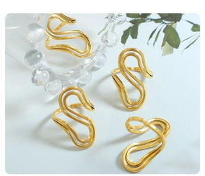 Macro detail of adjustable S-shaped gold-plated wave rings with high-polished metal finish