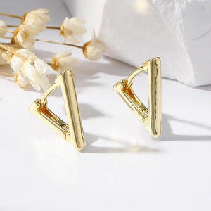 Minimalist gold geometric triangle hoop earrings displayed on white textured surface