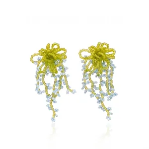 Detail of handmade green flower bead earrings with light blue fringe tassels for summer