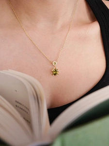 Macro shot of 18K gold plated necklace featuring an emerald green oval pendant on a model