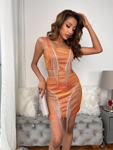 Close-up of orange sequin fabric with silver chain tassels on high-end mini skirt set