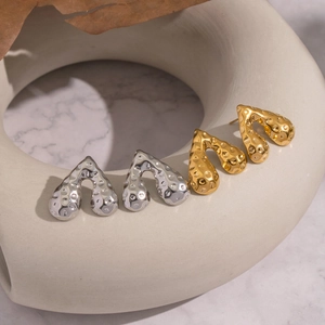 Abstrakte Hammerschlag-Herzohrringe in Gold und Silber auf Keramik-Displayständer