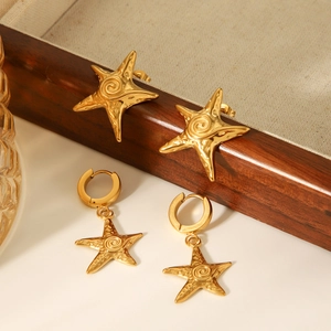 Detail of gold starfish earrings and studs with spiral texture on wood tray