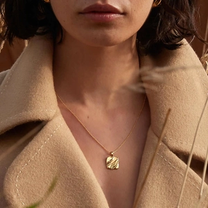 Detail of square gold textured pendant necklace on model with Baroque pearl accents