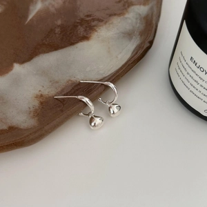 Minimalist 925 sterling silver heart dangle earrings on a luxury ceramic tray