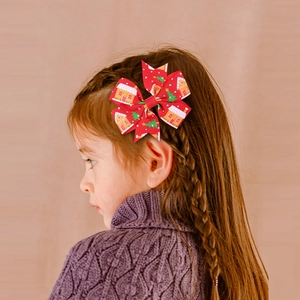 Close-up of a red Christmas bow hair clip with festive prints worn by a young girl