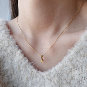 Dettaglio di una collana in titanio dorato con ciondolo in pietra portafortuna gialla sul collo