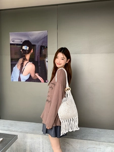 Close-up of beige woven mesh bag with fringe hem and round wooden handles