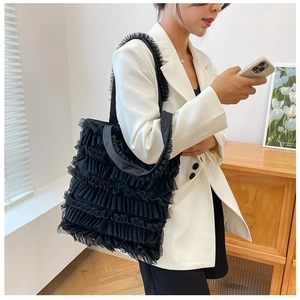 Détail d'un cabas en tulle noir à volants porté sur un blazer blanc contrasté