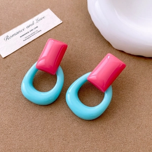 Detail of geometric resin earrings in rose pink and sky blue colors on a brown base