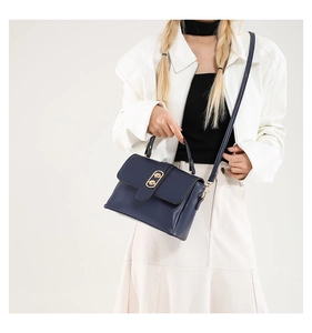 Close-up of dark blue leather handbag with elegant gold oval double buckle hardware detail