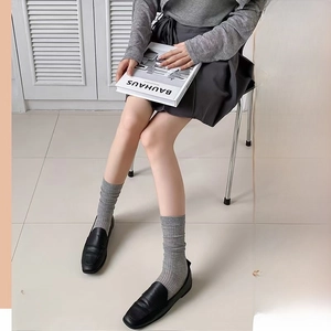 Detailed view of grey vertical striped knee-high socks with black loafers for a chic JK style