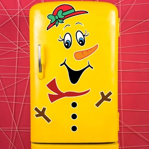 Detail of Christmas snowman magnetic sticker on a yellow vintage fridge with red wall background