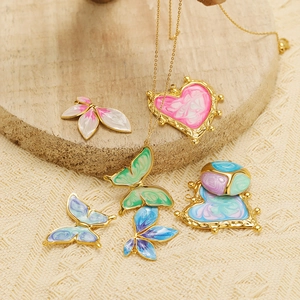 Detailed view of heart and butterfly pendants in gold with colorful enamel on wood