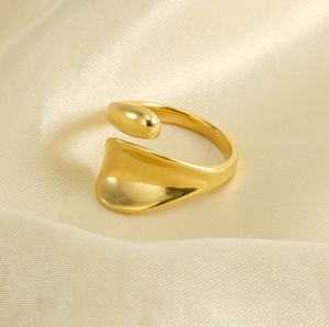 Detailed view of the gold wavy wide-band adjustable ring on elegant beige silk fabric
