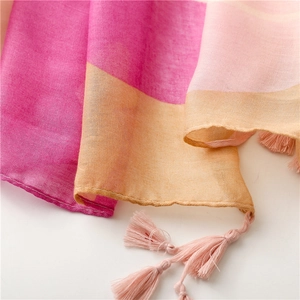 Detailed close-up of vibrant pink and orange floral scarf with delicate fringe tassels