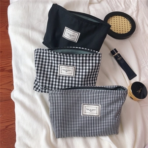 Detail of three black and white checkered cotton makeup bags with Time To Party logo tags