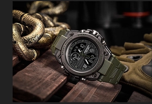 Tactical dual display sport watch with military green strap on a rugged metal background