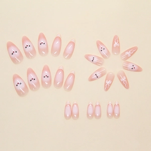Détail de faux ongles amande avec motifs chat et nœud en dégradé rose et blanc