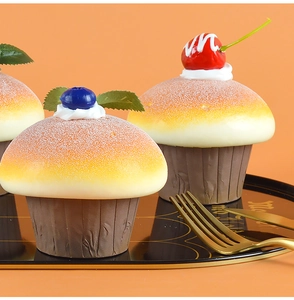 Detail of realistic artificial cupcakes with cherry and blueberry toppings on a tray