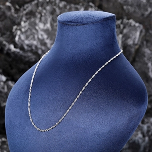 Close-up of silver water wave chain necklace on a velvet bust against dark stone background