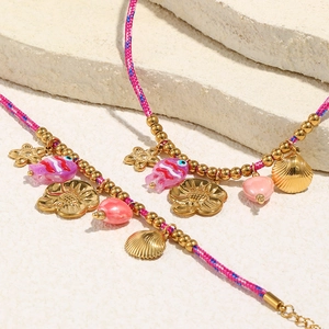 Détail d'un bracelet de cheville bohème tressé avec breloques coquillage et poisson