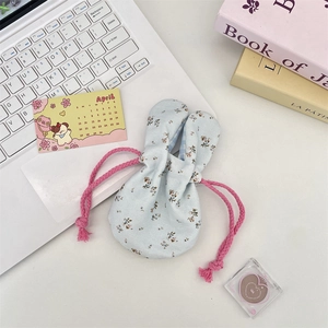 Floral bunny ear drawstring storage bag on a bright desk with lifestyle props