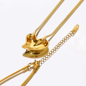 Detailed macro view of 18k gold heart pendant necklace with snake chain on white surface
