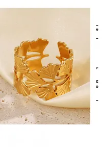 Détail d'une bague feuille de ginkgo dorée brossée sur fond soie et pierre
