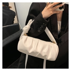 Close-up of white ruched cloud bag with knotted handle detail worn with a black blazer
