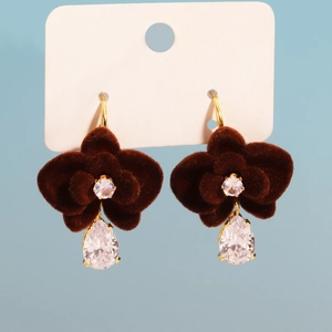 Detailed close-up of dark red velvet flower earrings with drop zircon on card