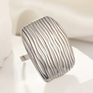 Detailed view of silver titanium steel ring with textured wave pattern on a stone base