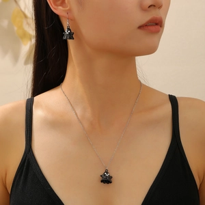 Detail shot of a model wearing a cute black ghost pendant necklace and matching earrings