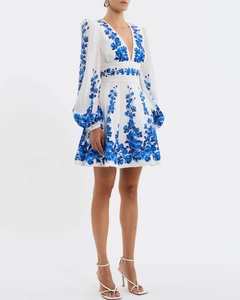 Detailed view of deep V-neck white dress with blue floral embroidery and lantern sleeves