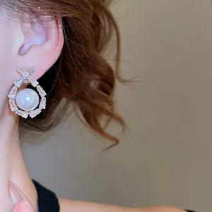 Elegant geometric pearl drop earrings with baguette zircon frame on female model