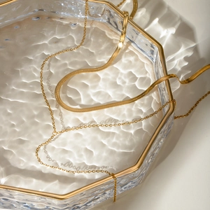 Gold double-layered stainless steel snake chain necklace in a luxury glass tray