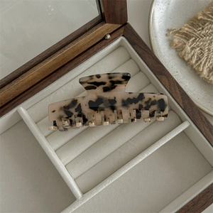 Detail view of large leopard print acetate hair claw clip on a rustic wooden box