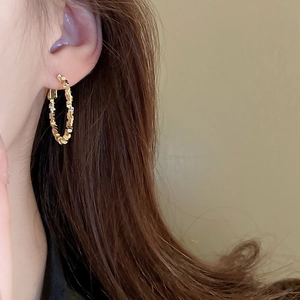 Close-up of irregular textured golden hoop earring worn on model for a minimalist look