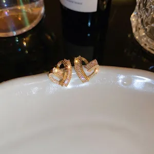Elegant gold-plated heart stud earrings with sparkling cubic zirconia on white porcelain