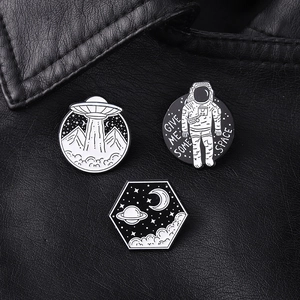 Detailed view of 3 astronaut enamel pins featuring UFO and space motifs on black leather