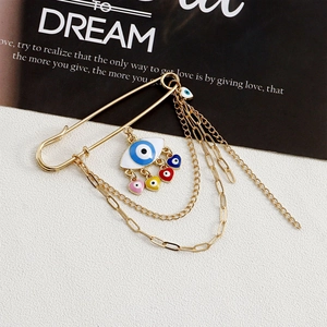 Detail of gold evil eye safety pin brooch with colorful enamel hearts and long tassels