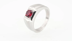 Detail view of a men's silver stainless steel ring with a large round red gemstone