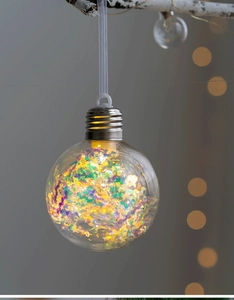 Detail of Christmas ornament ball with colorful holographic foil and warm LED bokeh lighting