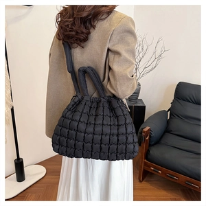 Detail of black quilted shoulder bag featuring bubble texture and soft puffer design
