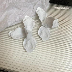 Macro detail of matte white flower petals earrings with stylish 3D floral texture