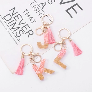 Detail view of J, K, L letter keychains with pink resin, gold glitter, and soft tassels