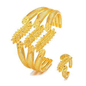 Close-up of gold hollow filigree bangle and ring set with intricate leaf motifs