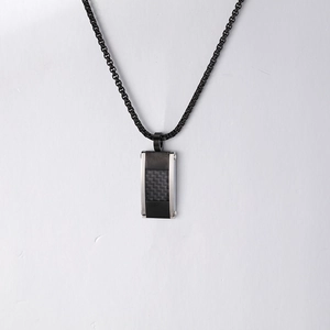 Détail macro du pendentif rectangulaire en fibre de carbone sur chaîne en acier noir