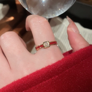 Macro shot of a red enamel ring with a square zircon stone on a woman's hand