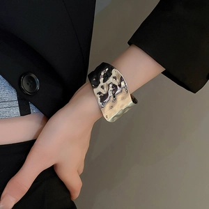 Detail of a wide silver irregular hammered texture cuff bracelet on a model's wrist